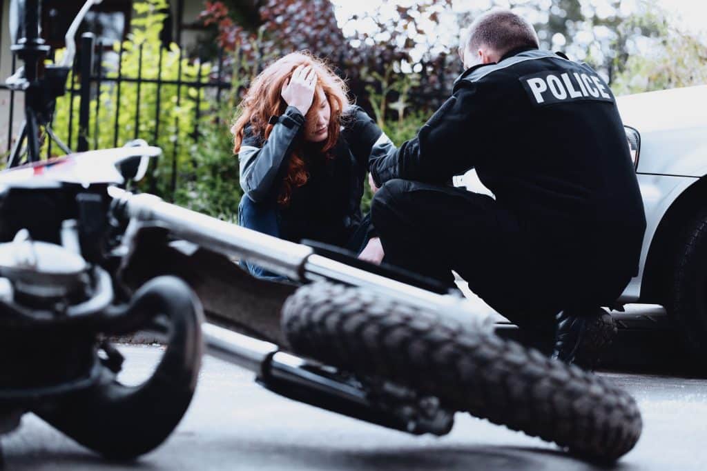 A woman looking distressed talking to a police officer after a motorcycle accident