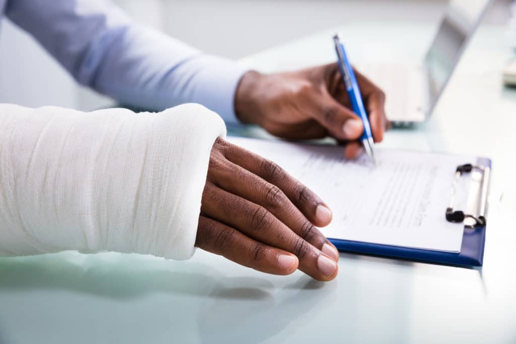 A man with a cast on his arm filling out information about his personal injury accident.