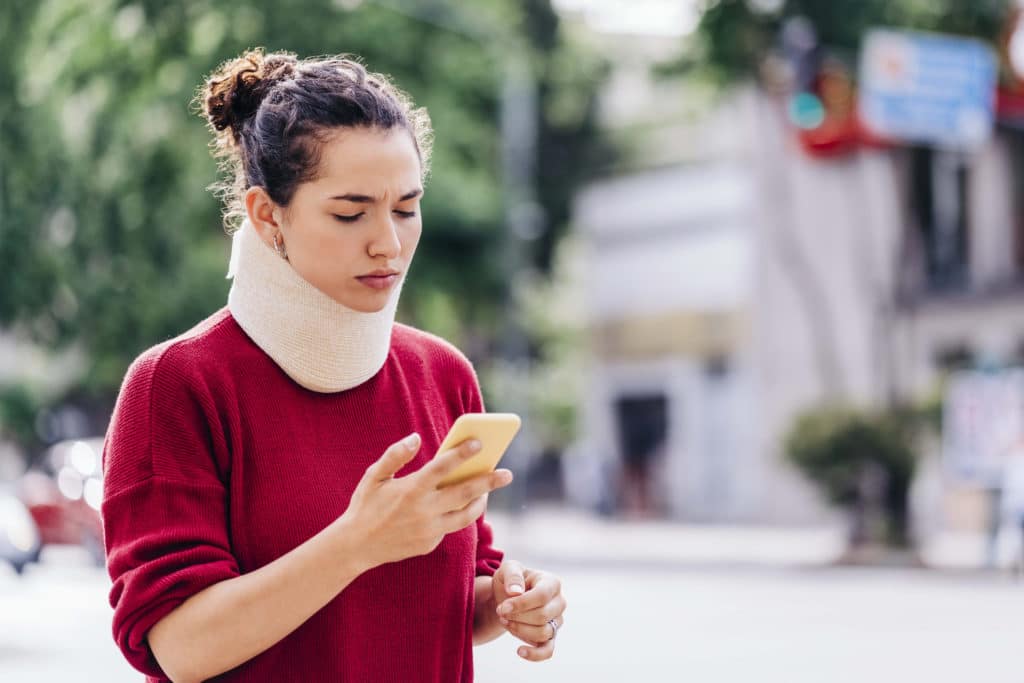 An injured woman with a neck brace contacting her Tulsa, OK, personal injury lawyer.