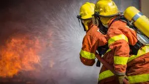 2 firefighters spraying high pressure water to fire