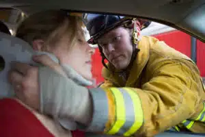 A first responder putting a neck brace on a woman after a car accident. 