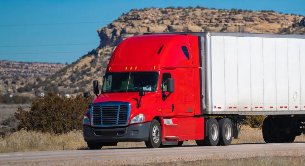 Eighteen wheel big rig tractor with trailer on highway. Trucking industry