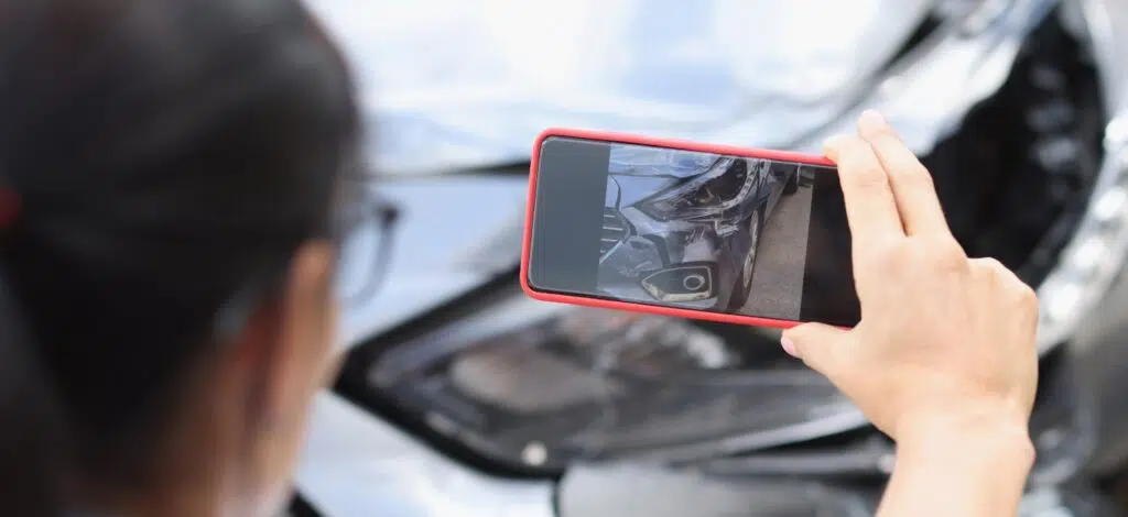 A person taking photos with a cell phone to document the details after a car accident