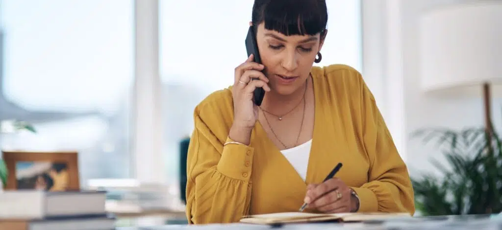 A person making notes while talking on the phone after a car crash