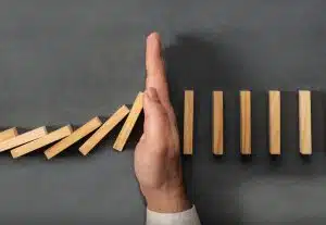 mans hand blocking dominos from falling