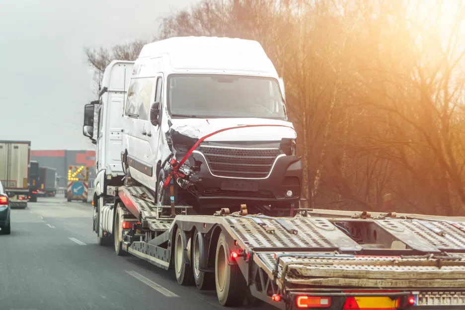 damaged commercial vehicle on a flatbed trailer after an accident