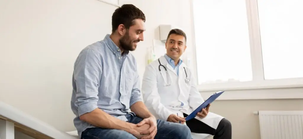 Young man sitting with doctor reviewing his chart