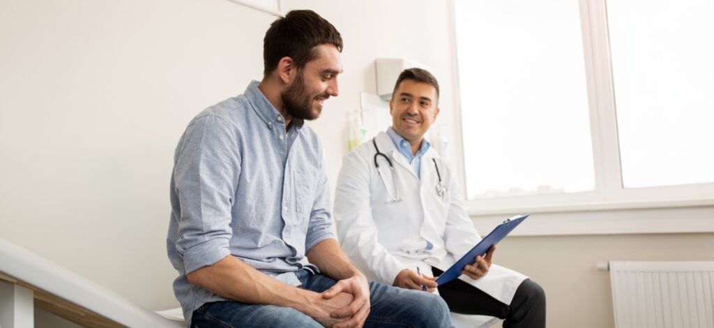 Young man sitting with doctor reviewing his chart