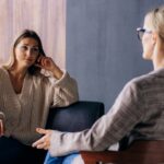 Woman sits comfortably on couch sitting across from her therapist