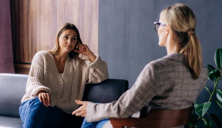Woman sits comfortably on couch sitting across from her therapist