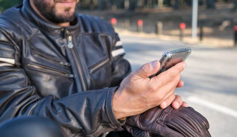A motorcycle driver stopped on the road and holding his phone after a motorcycle accident