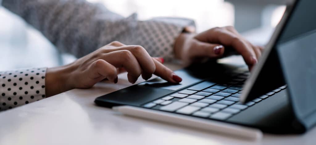 Image of a woman's hands typing at a computer.