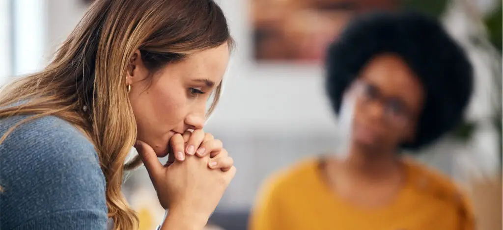 A woman sits pensively, hands on her chin, as she considers how to respond to an interview question.