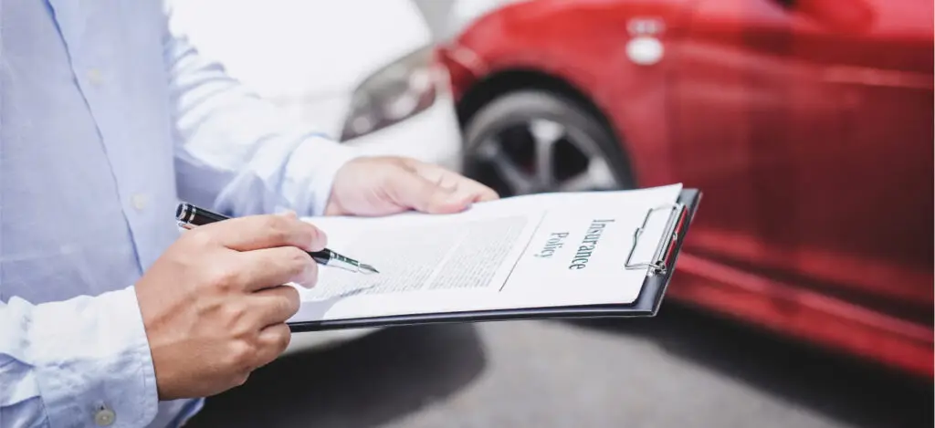 A man with a clipboard reviews an insurance policy after a car accident