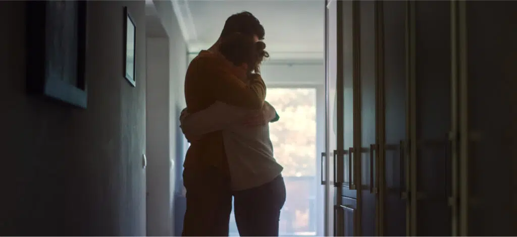 Two family members, a young man and a young woman, embrace in grief after the wrongful death of a loved one.