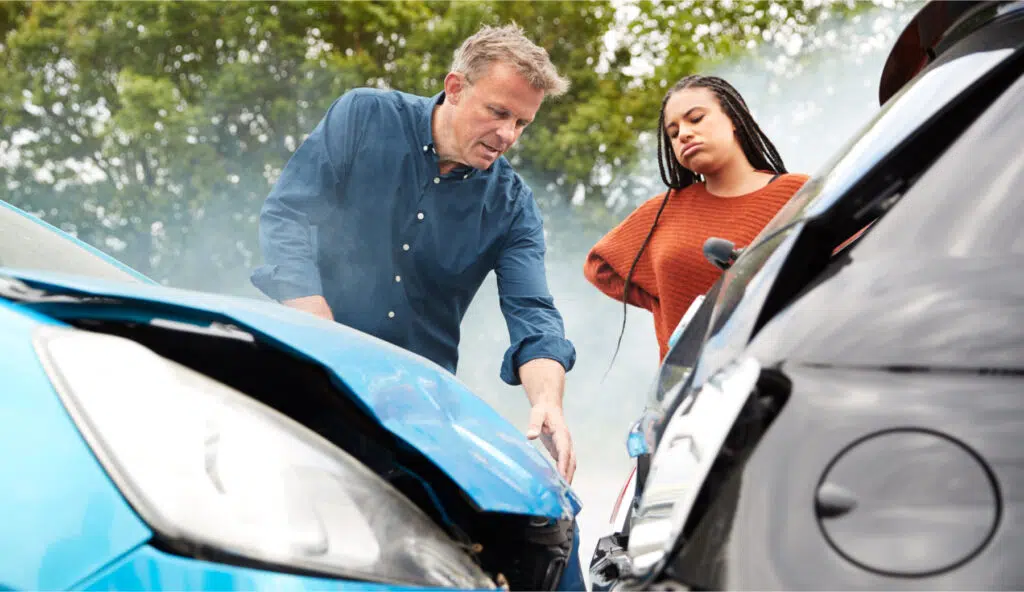 Two people examining the damage after a multi-car accident