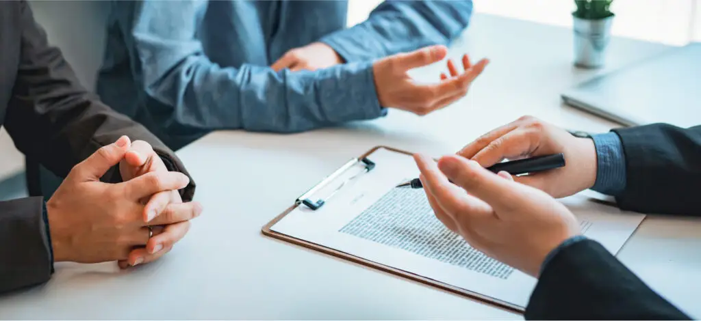 A close-up of hands and paperwork on a clipboard during a discussion