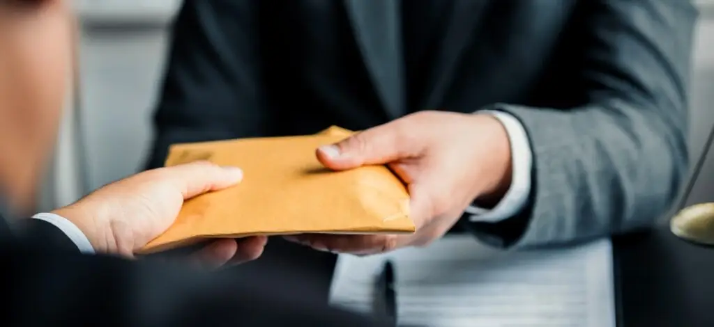 A man hands over an envelope containing a confidential settlement