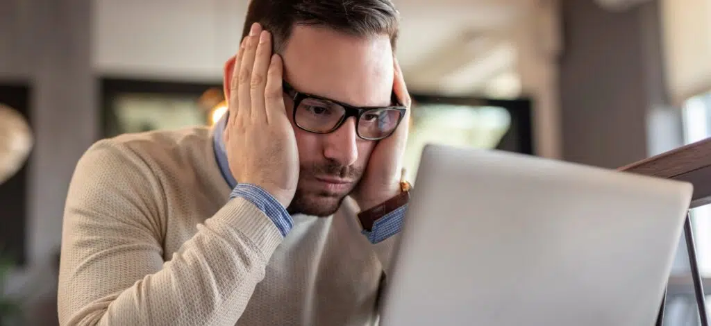A man stresses out as he looks at information on his laptop computer