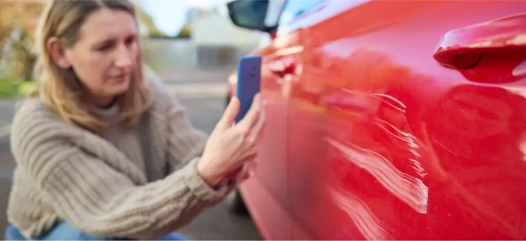 A person taking photos of damage from a car accident