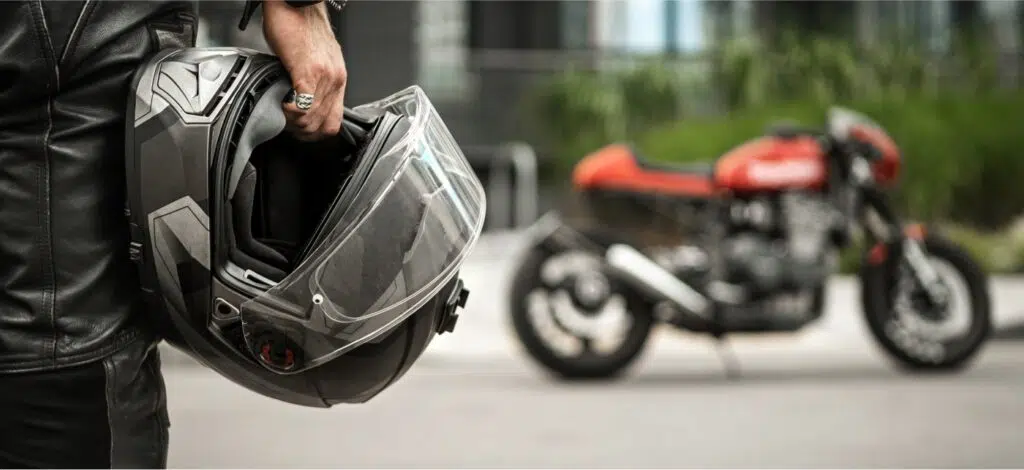 A person holding a helmet and looking at a motorcycle