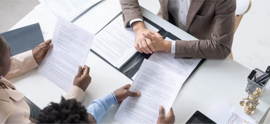 An African America couple meets with a personal injury attorney and they review documents in a bright, contemporary law office.