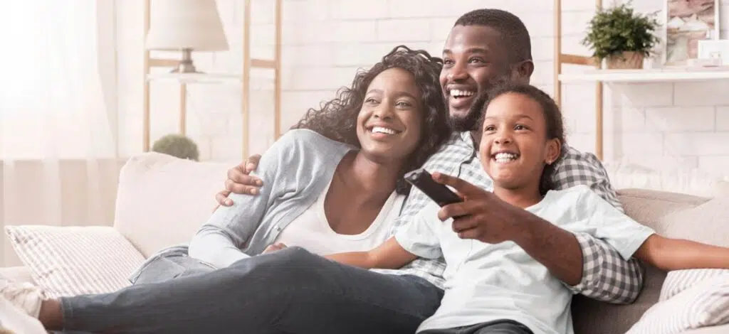 a family smiling and sitting together on the couch watching a movie