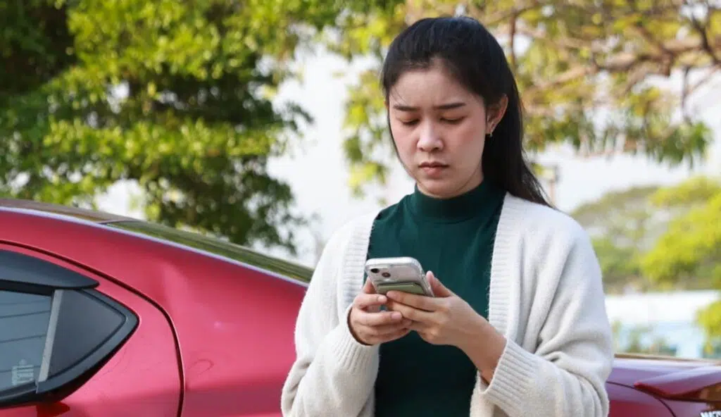 a woman looking at a cell phone after a car accident out of state