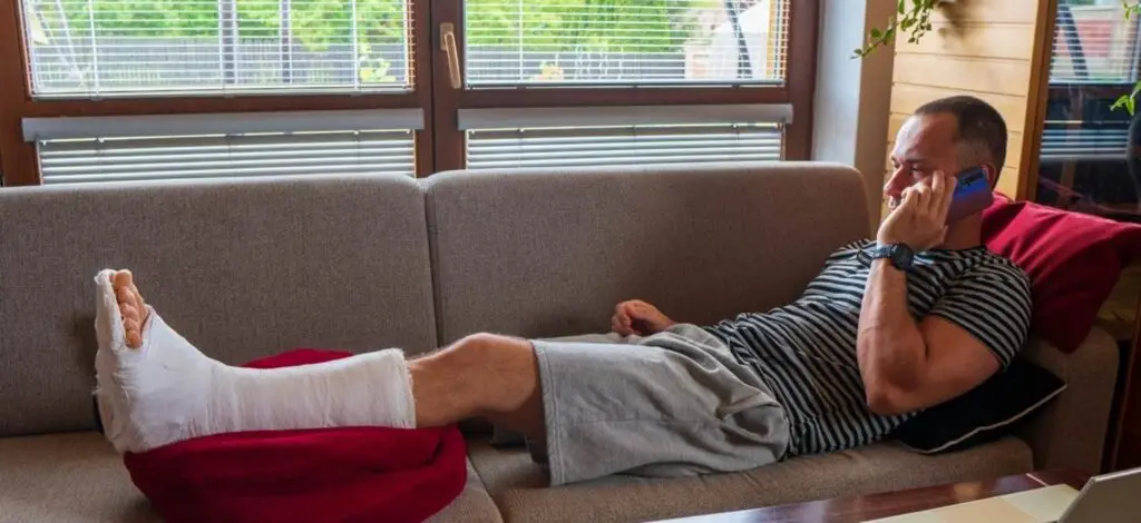 a person on the phone while lying on the couch with a cast on his leg