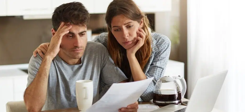 a couple with concerned expressions reviewing paperwork