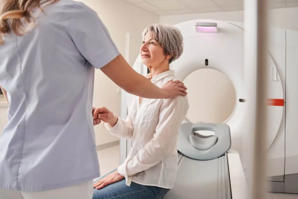 a woman sitting in front of an imaging machine to check for brain injuries