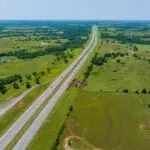 Aerial view of a highway running through green fields and farmland.
