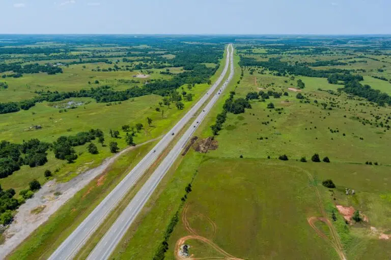 Aerial view of a highway running through green fields and farmland.