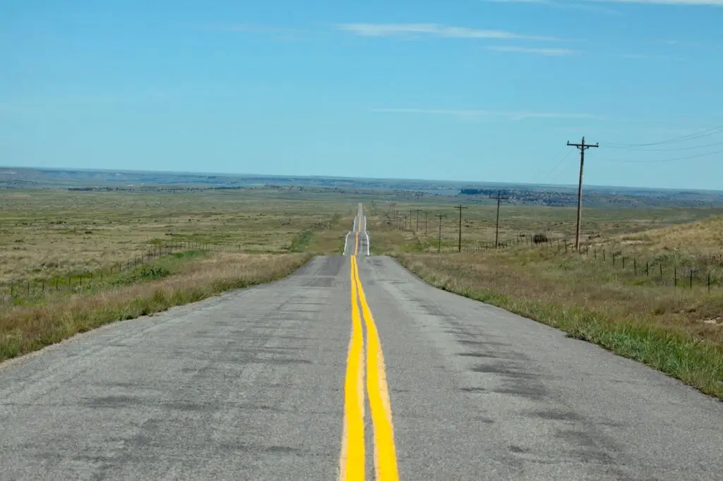 Long rural road with a yellow center line stretching across open countryside.