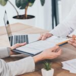Close-up of two people exchanging insurance documents