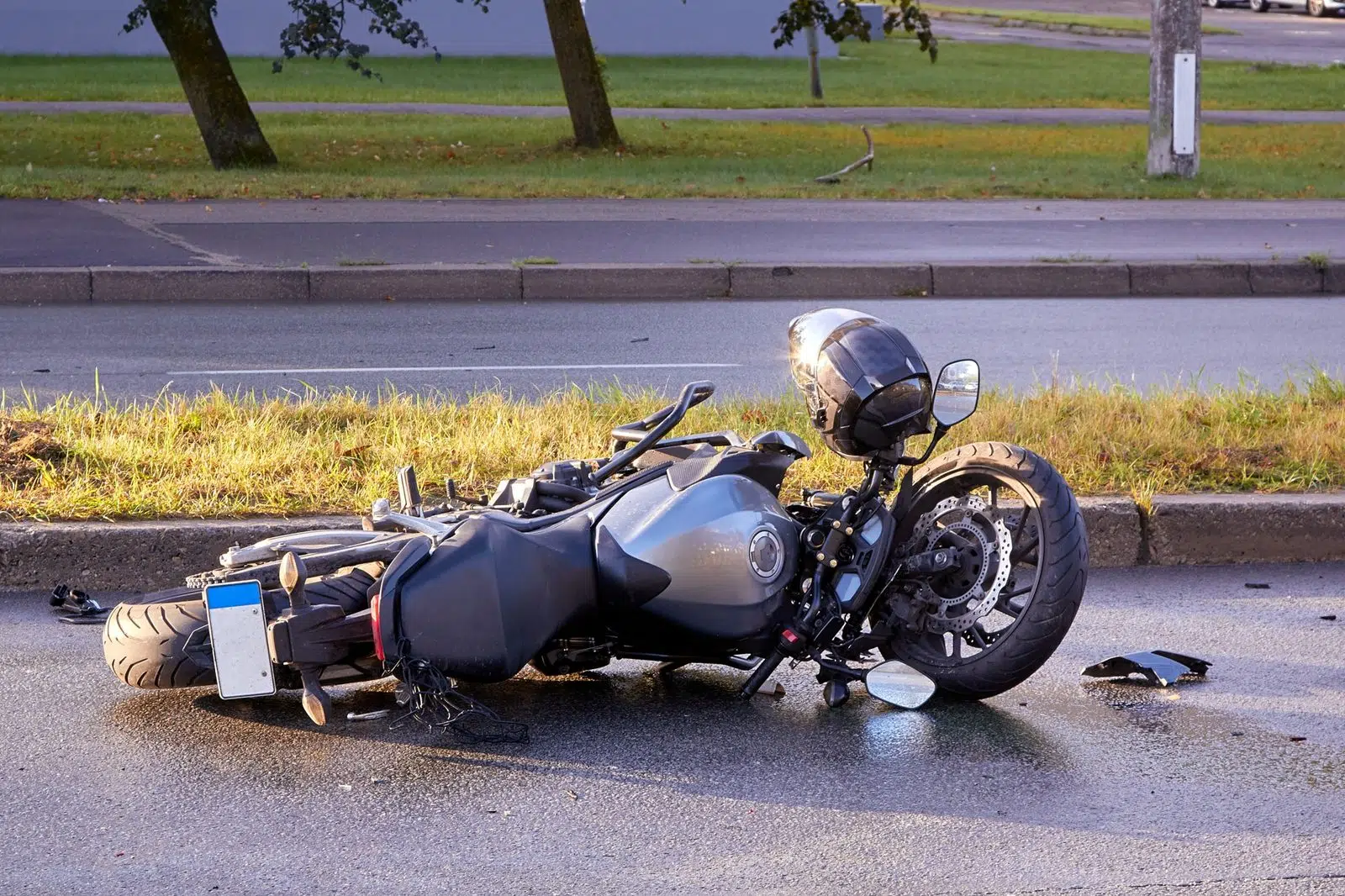 A fallen motorcycle lying on its side on an asphalt road after an Ardmore, OK motorcycle accident, with a helmet on the ground beside it