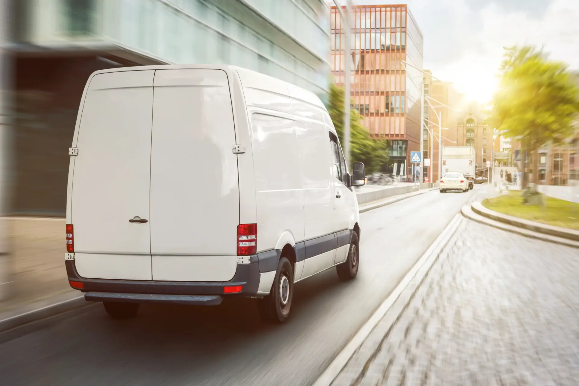 White commercial delivery van driving through a city street with motion blur