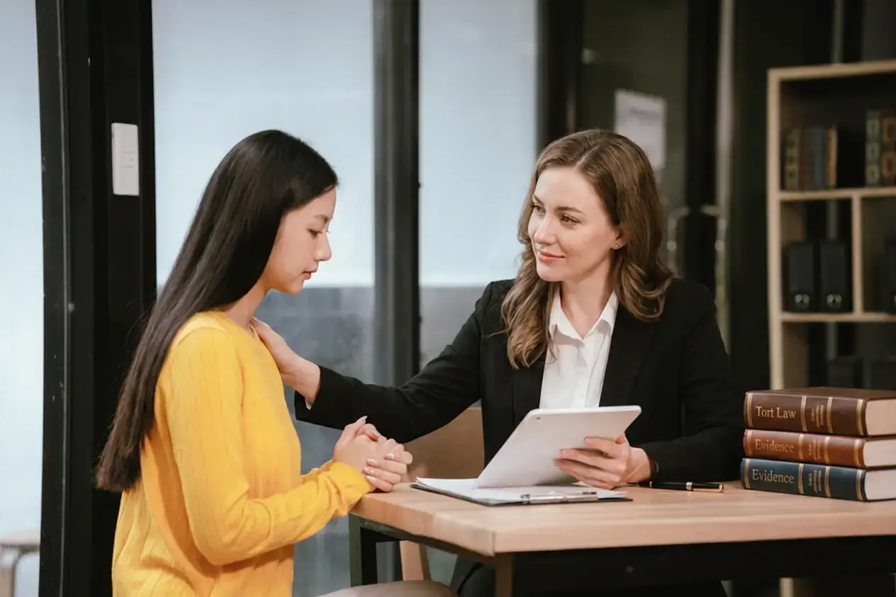 Tulsa disability attorney comforting a client during a consultation with legal reference books on the desk